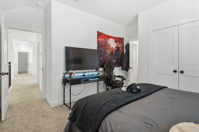 bedroom featuring lofted ceiling, baseboards, a closet, and light carpet