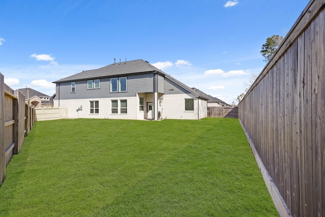 back of house featuring a yard and a fenced backyard