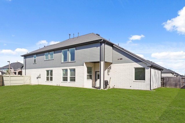 rear view of property featuring a fenced backyard, brick siding, and a yard