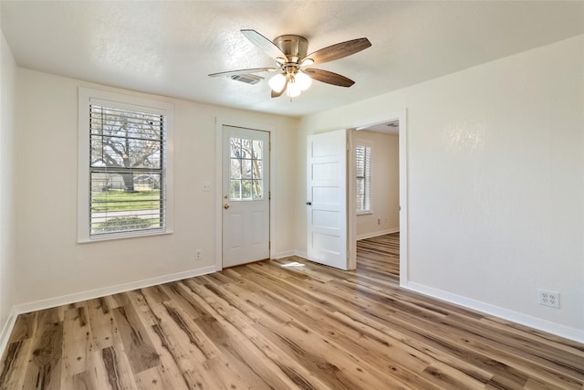 unfurnished room featuring visible vents, baseboards, ceiling fan, light wood-style floors, and a textured ceiling