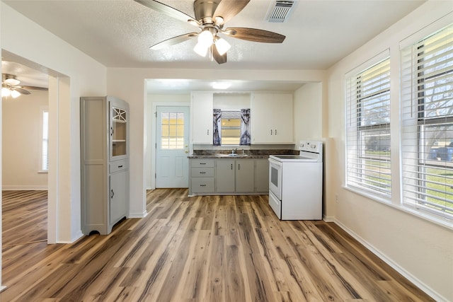 kitchen with light wood-type flooring, visible vents, a wealth of natural light, and white electric range oven