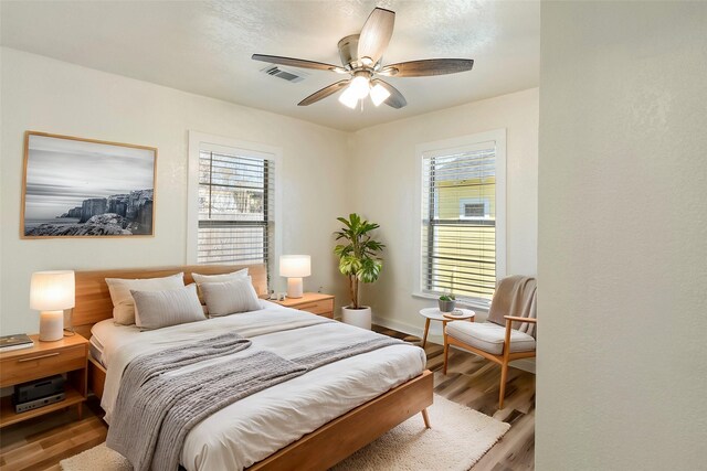 bedroom with visible vents, multiple windows, ceiling fan, and wood finished floors