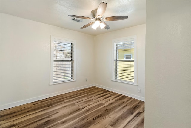 spare room with wood finished floors, baseboards, and a healthy amount of sunlight