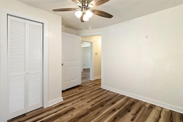 unfurnished bedroom with a closet, baseboards, wood finished floors, and a ceiling fan