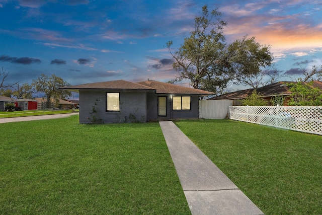 view of front of home with brick siding, a front lawn, and fence