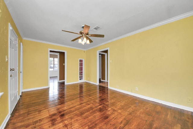 empty room with crown molding, wood finished floors, and baseboards