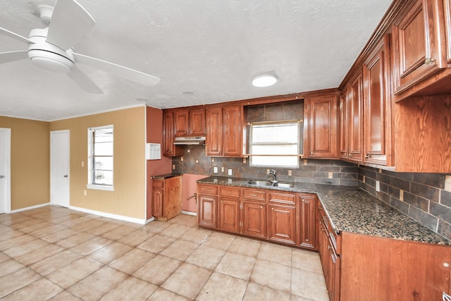 kitchen featuring a sink, backsplash, ceiling fan, and brown cabinetry