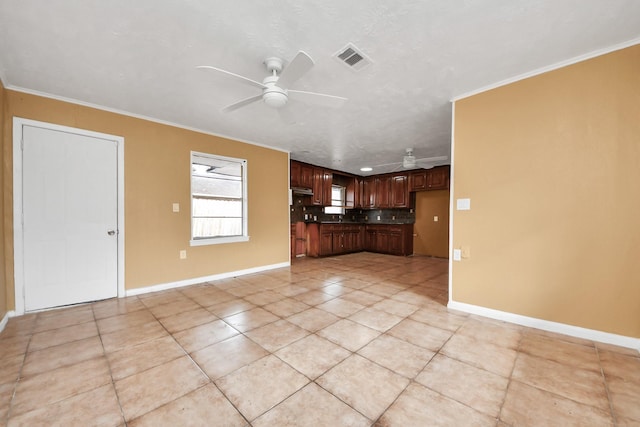 kitchen with a ceiling fan, baseboards, visible vents, crown molding, and dark countertops