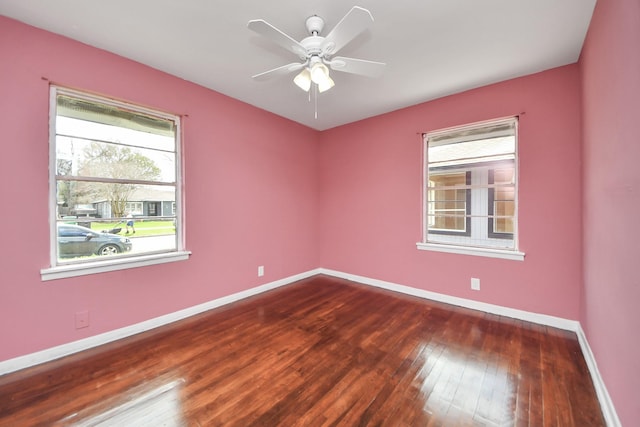 spare room with a ceiling fan, dark wood-style floors, and baseboards