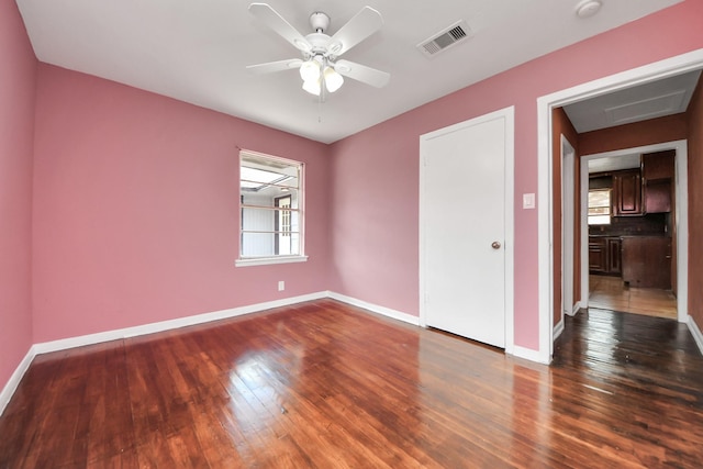 empty room with ceiling fan, visible vents, baseboards, and dark wood-style floors