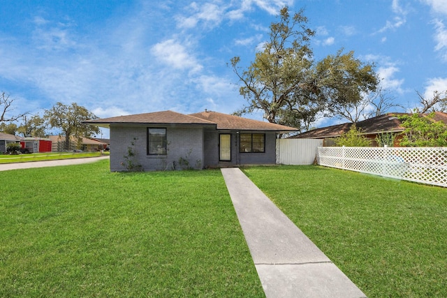 view of front of home with brick siding, a front lawn, and fence