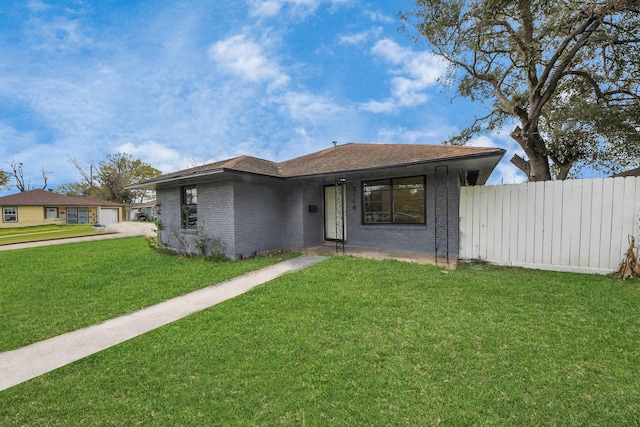 view of front of property with fence, roof with shingles, a front yard, a garage, and brick siding