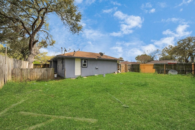 back of house with a lawn and a fenced backyard