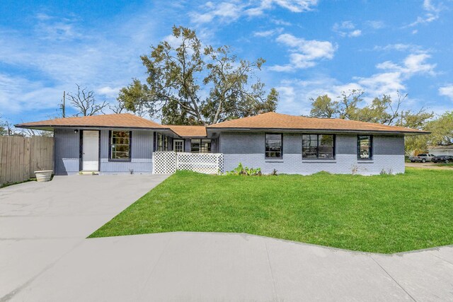 ranch-style home featuring brick siding, concrete driveway, a front lawn, and fence