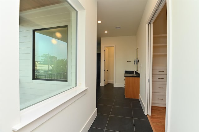 corridor featuring recessed lighting, baseboards, and dark tile patterned flooring