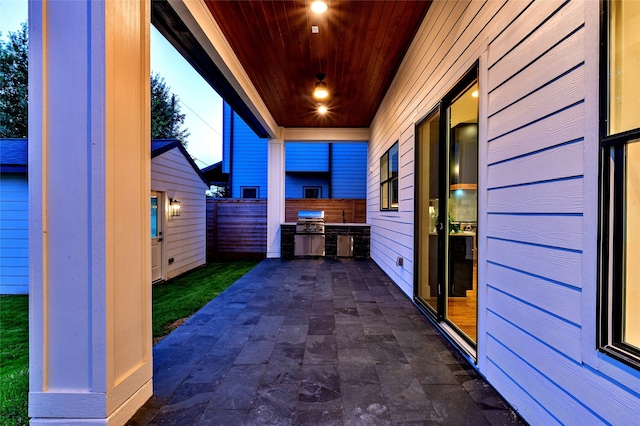 view of patio featuring grilling area, an outbuilding, and fence