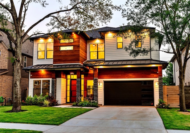 contemporary house featuring a front lawn, metal roof, driveway, an attached garage, and a standing seam roof