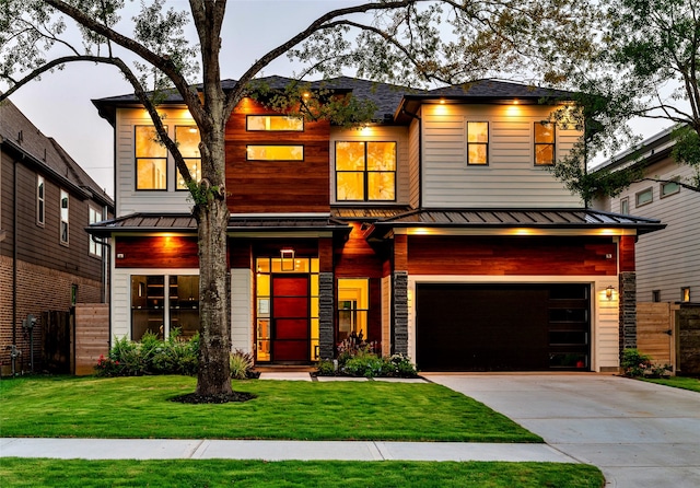 view of front of home featuring a standing seam roof, a front yard, a garage, and metal roof