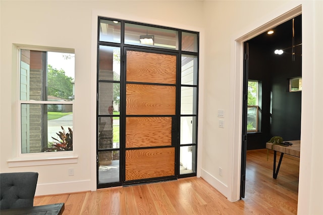 doorway featuring plenty of natural light, wood finished floors, and baseboards