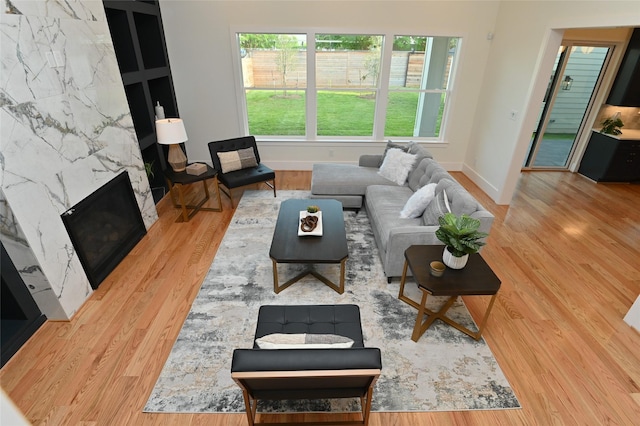 living area featuring wood finished floors, baseboards, and a high end fireplace