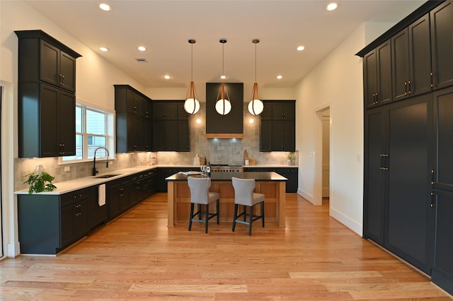 kitchen featuring a kitchen breakfast bar, light wood-type flooring, a center island with sink, and a sink