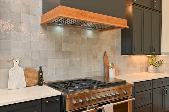 kitchen with custom exhaust hood, high end stove, and tasteful backsplash