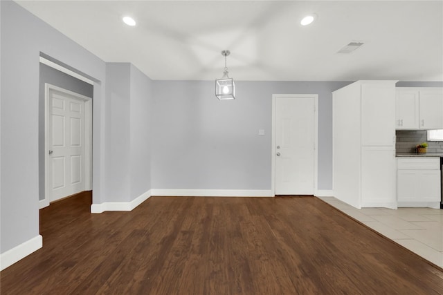 unfurnished dining area with visible vents, recessed lighting, baseboards, and wood finished floors