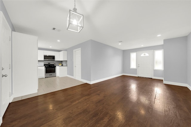 unfurnished living room with hardwood / wood-style flooring, recessed lighting, baseboards, and visible vents