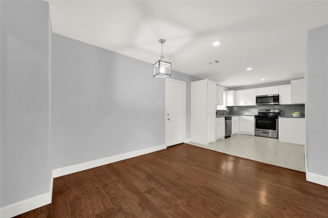 kitchen with visible vents, wood finished floors, white cabinetry, stainless steel appliances, and decorative backsplash