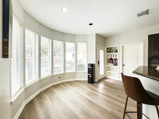 kitchen with visible vents, baseboards, a textured ceiling, and light wood finished floors