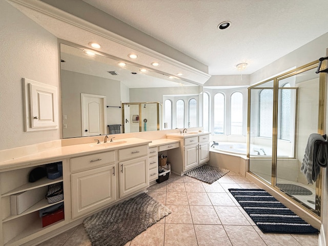 bathroom featuring tile patterned flooring, a shower stall, a bath, and a sink