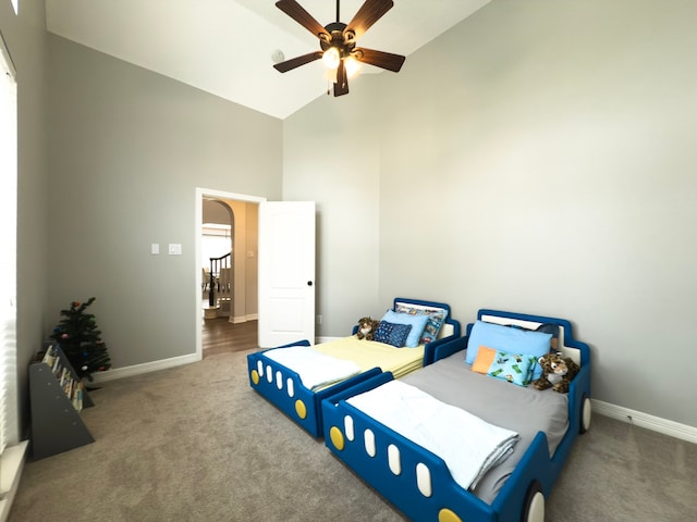 carpeted bedroom with a ceiling fan, baseboards, and high vaulted ceiling