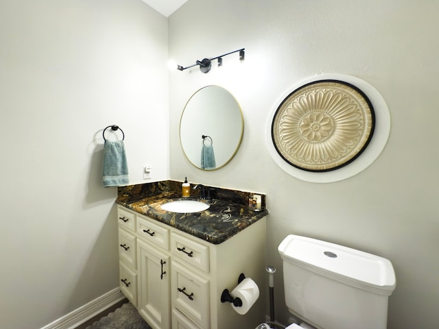 bathroom featuring baseboards, toilet, and vanity