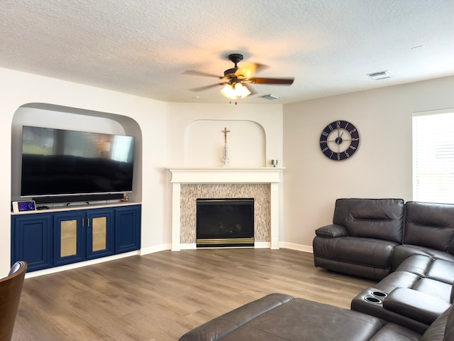 living room with a tiled fireplace, wood finished floors, visible vents, and a textured ceiling