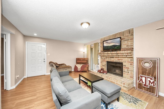 10555 Turtlewood Ct Unit 1510, Houston, TX 77072 - living room with a fireplace, light wood-style flooring, a textured ceiling, and baseboards