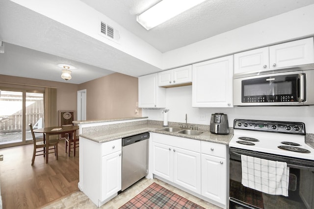 10555 Turtlewood Ct Unit 1510, Houston, TX 77072 - kitchen with a peninsula, white cabinets, visible vents, a sink, and stainless steel appliances