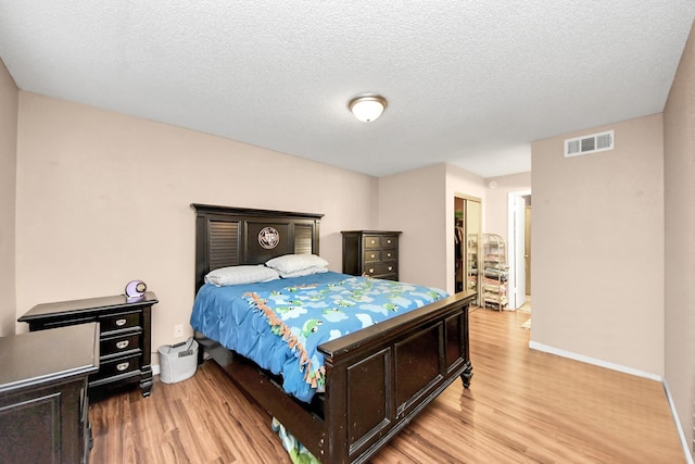 10555 Turtlewood Ct Unit 1510, Houston, TX 77072 - bedroom featuring visible vents, baseboards, a textured ceiling, and wood finished floors