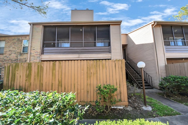 10555 Turtlewood Ct Unit 1510, Houston, TX 77072 - view of front of home featuring a sunroom, a chimney, fence, and stairs