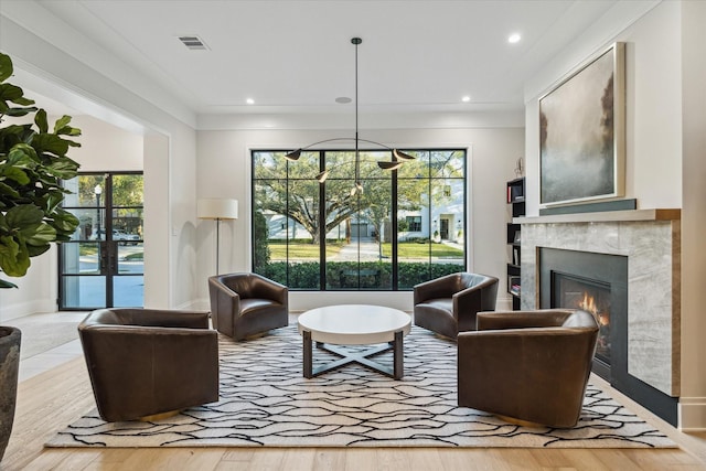 living area featuring visible vents, a healthy amount of sunlight, a fireplace, and wood finished floors