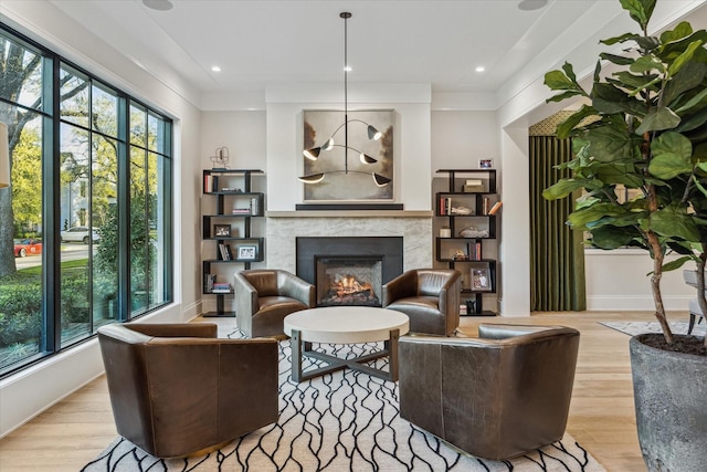 living area with recessed lighting, wood finished floors, baseboards, and a premium fireplace