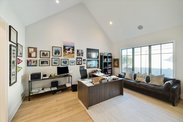 office area featuring baseboards, high vaulted ceiling, and light wood-style flooring