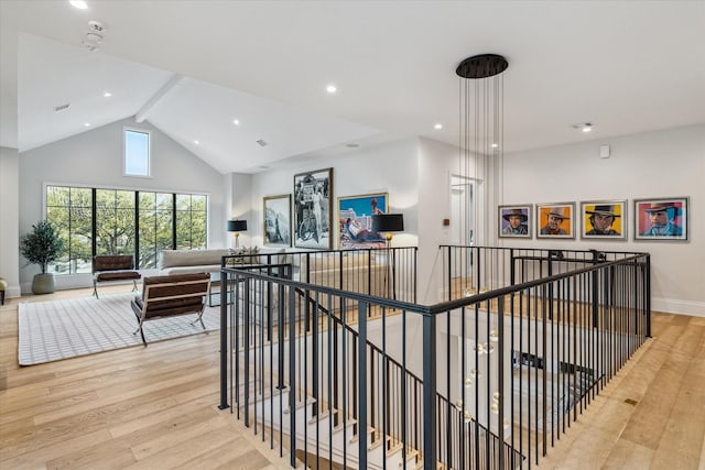 corridor featuring light wood-type flooring, an upstairs landing, high vaulted ceiling, beam ceiling, and baseboards