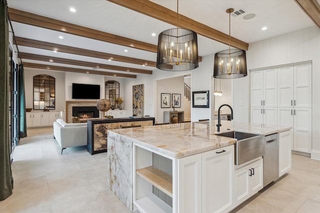 kitchen with an island with sink, a sink, open shelves, stainless steel dishwasher, and a lit fireplace