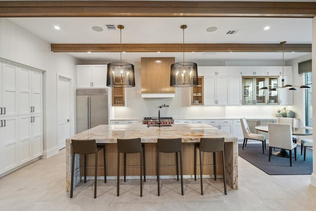 kitchen with visible vents, glass insert cabinets, beamed ceiling, built in refrigerator, and white cabinetry