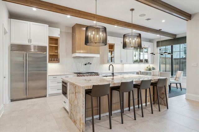 kitchen featuring beamed ceiling, visible vents, built in refrigerator, and a sink