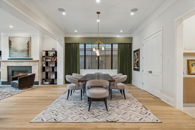 dining area with recessed lighting, a glass covered fireplace, light wood-style flooring, and an inviting chandelier