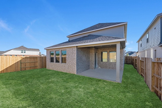 rear view of property featuring a patio, roof with shingles, a fenced backyard, a lawn, and brick siding