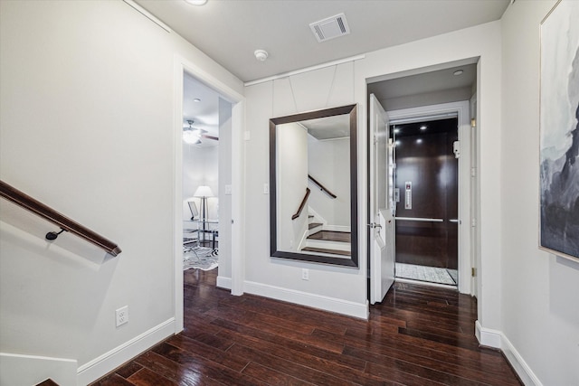 corridor featuring visible vents, baseboards, stairs, and hardwood / wood-style flooring