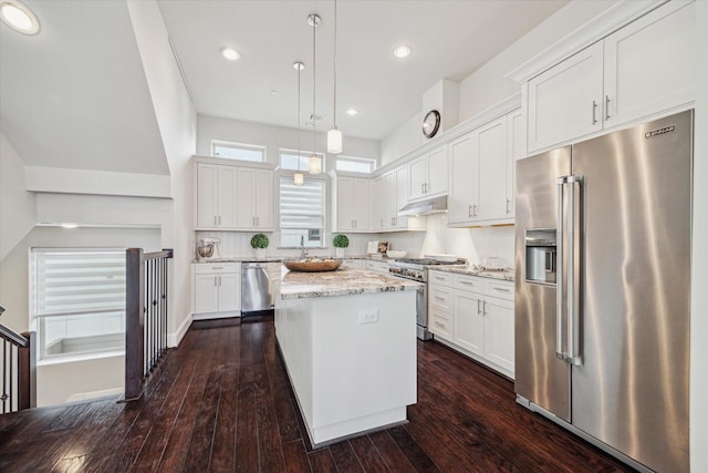 kitchen with under cabinet range hood, premium appliances, a kitchen island, and white cabinetry