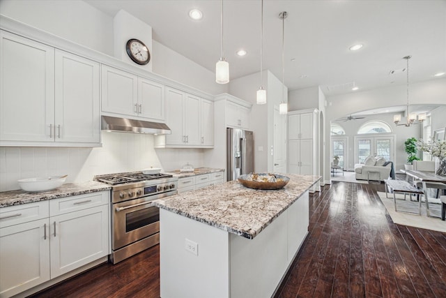 kitchen with dark wood-type flooring, under cabinet range hood, premium appliances, a kitchen island, and white cabinetry